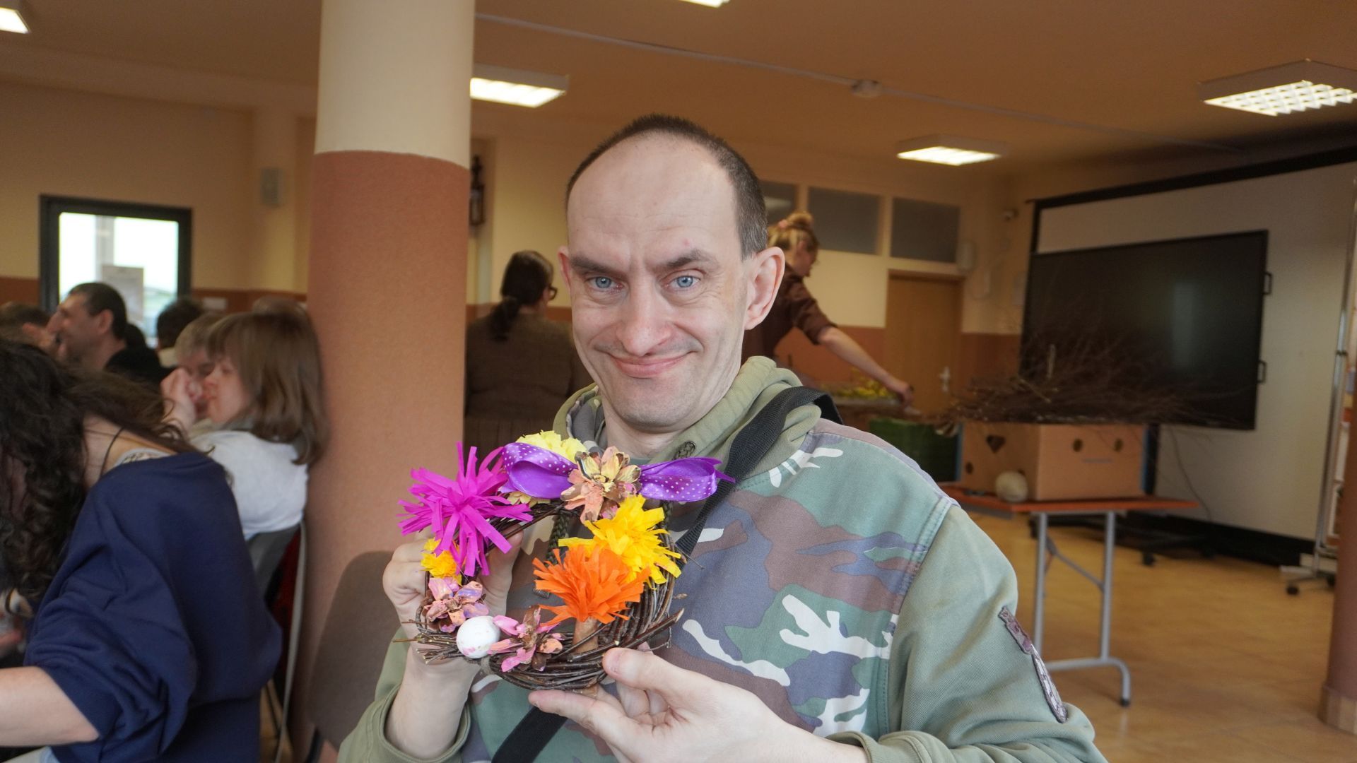 Uczestnik Paweł W. prezentuje wianek, który wykonał podczas wielkanocnych warsztatów artystycznych.