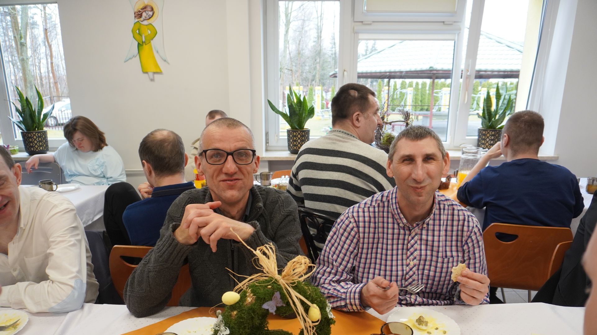 Uczestnicy, Grzegorz i Sebastian siedzą przy stole podczas spotkania wielkanocnego.