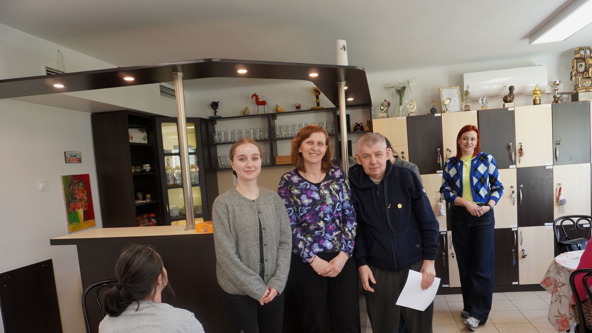 Uczestnik Sławomir odbiera dyplom i słodki upominek za zajęcie I miejsca w Turnieju Warcabowym 2026. 