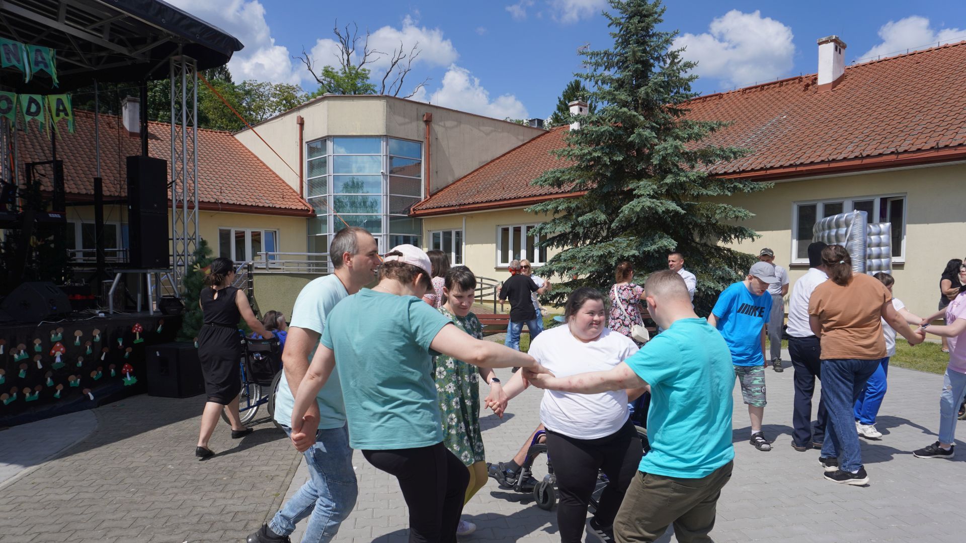 Uczestnicy naszego Domu tańczą w kółeczku podczas Pikniku Rodzinnego w DPS w Kątach.