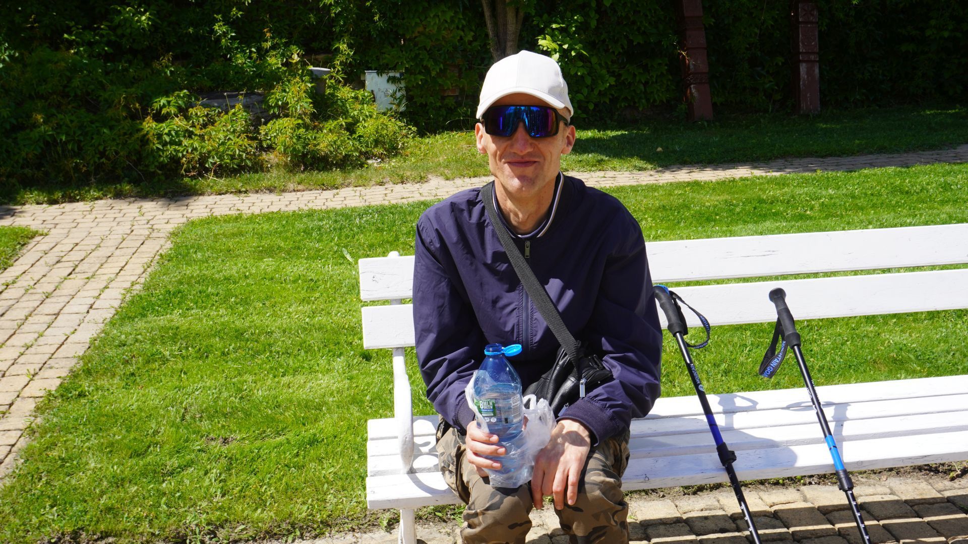 Uczestnik Grzegorz odpoczywa na ławce podczas spaceru z kijkami Nordic Walking.