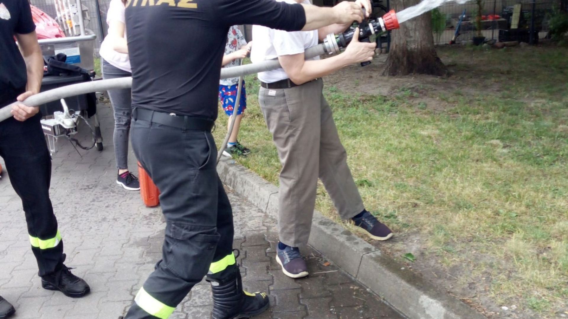 Uczestnik naszego Domu Sławomir leje wodę z węża strażackiego podczas II Powiatowego Dnia Bezpieczeństwa. 