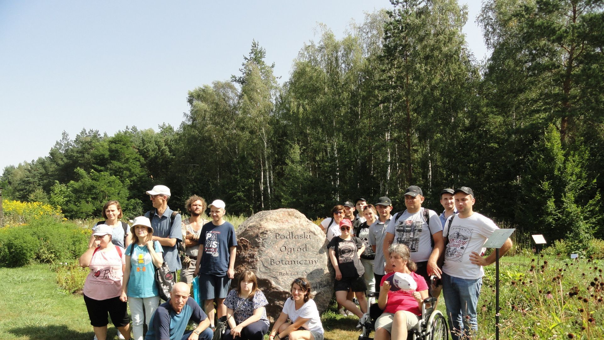 Uczestnicy i terapeuci przy kamieniu z napisem Podlaski Ogród Botaniczny.