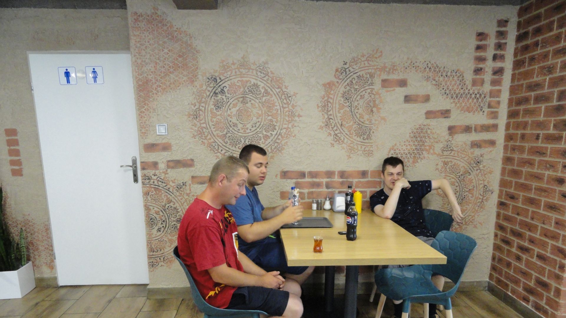Uczestnicy siedzą przy stoliku w restauracji i czekają na kebaby.