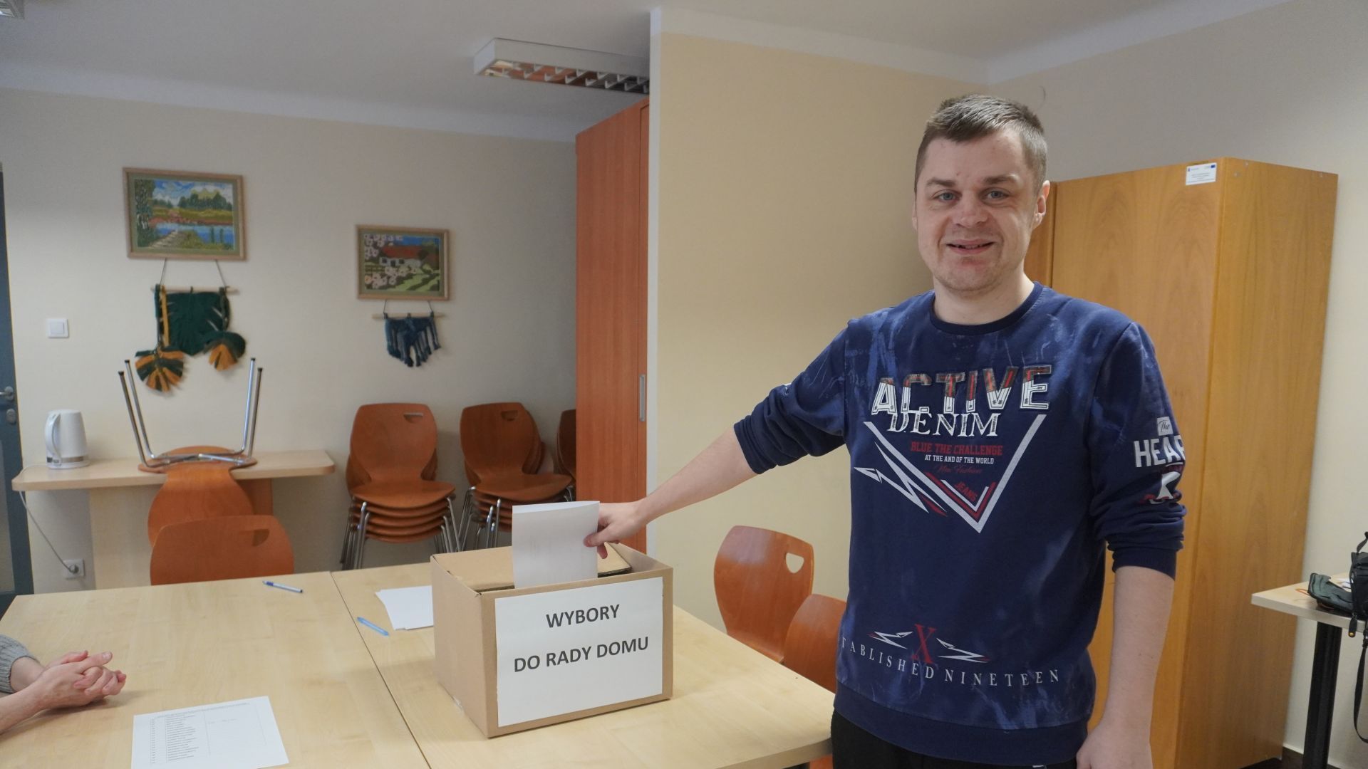 Uczestnik wrzuca kartę wyborczą do ''urny wyborczej''. 
