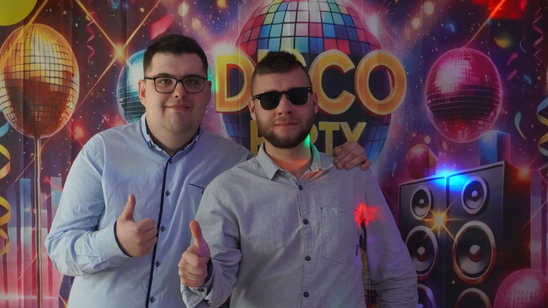 Uczestnicy Karol i Bartek pozują do zdjęcia na ściance z napisem Disco Party.